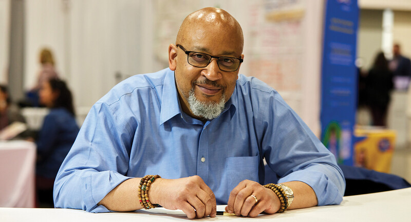 A photo of speaker and leadership consultant Baruti Kafele sitting at a table during an education conference.