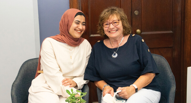 A mentor and mentee sitting side by side, smiling joyfully 